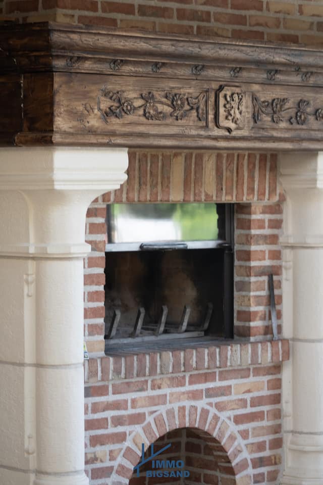 Open haard tussen witte zuilen in een bakstenen muur