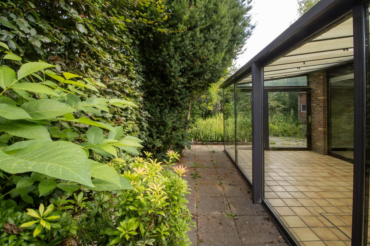 Veranda met glazen wanden in een groene tuin