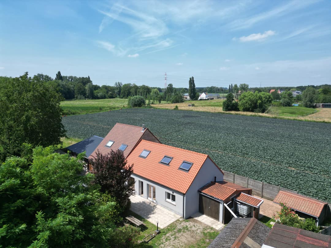 Woning met oranje dak naast een akker, van bovenaf